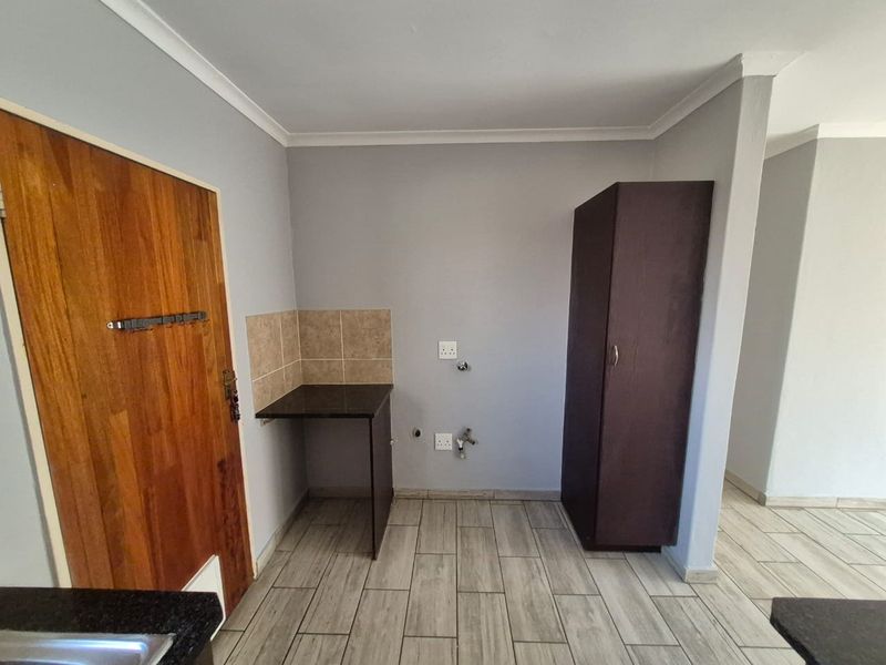 A functional laundry area featuring tiled flooring, a granite countertop with splashback, and dedicated plumbing connections for appliances.