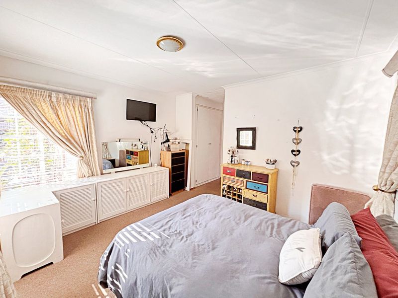 A functional bedroom featuring built-in cupboards, carpeted flooring, and a window with natural light.