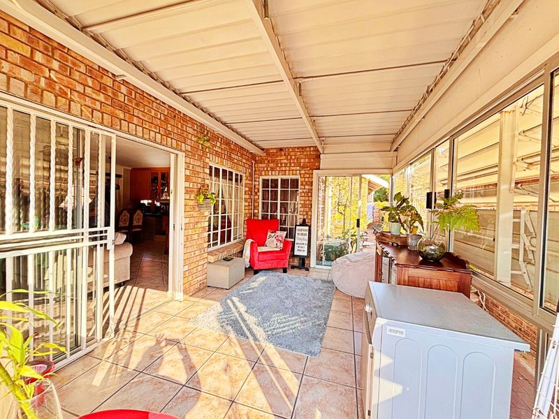 A covered patio area featuring exposed brick walls, tiled flooring, and a corrugated metal roof, providing a versatile outdoor living space.
