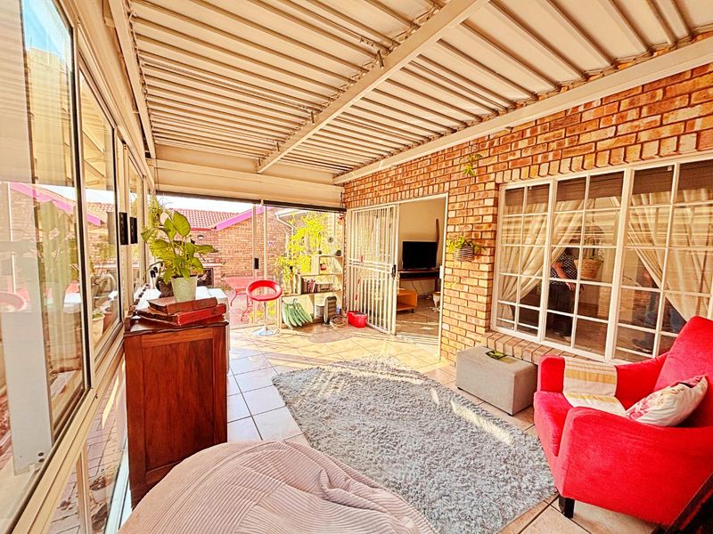 A covered patio area featuring exposed brick walls, tiled flooring, and large sliding glass doors providing access to the main living space.