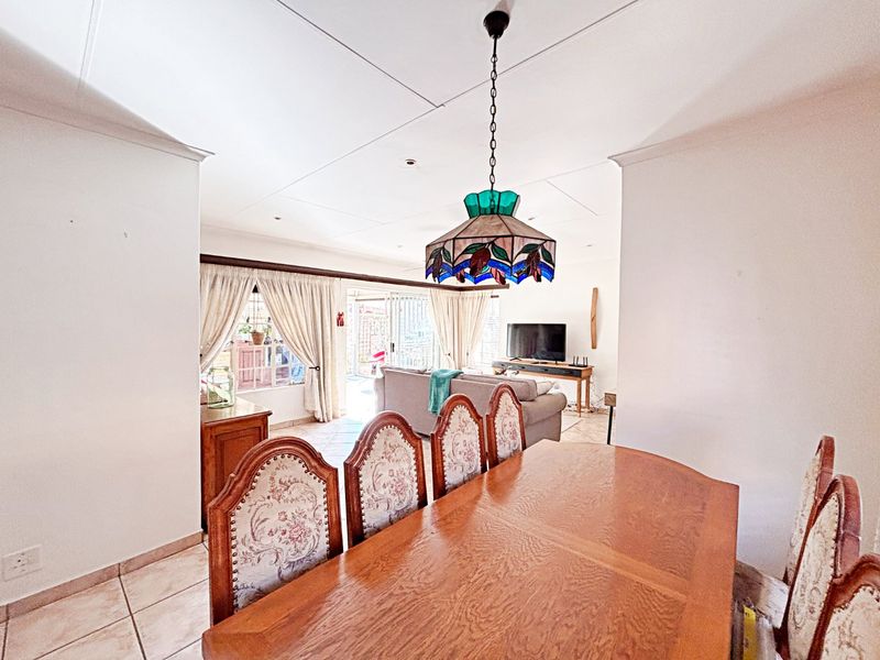 Open plan dining and living area featuring tiled floors, a decorative stained glass pendant light, and sliding glass doors leading to the outdoor space.