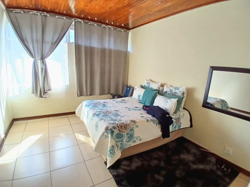 A bedroom featuring tiled flooring and a timber-paneled ceiling, offering a functional space with natural light.