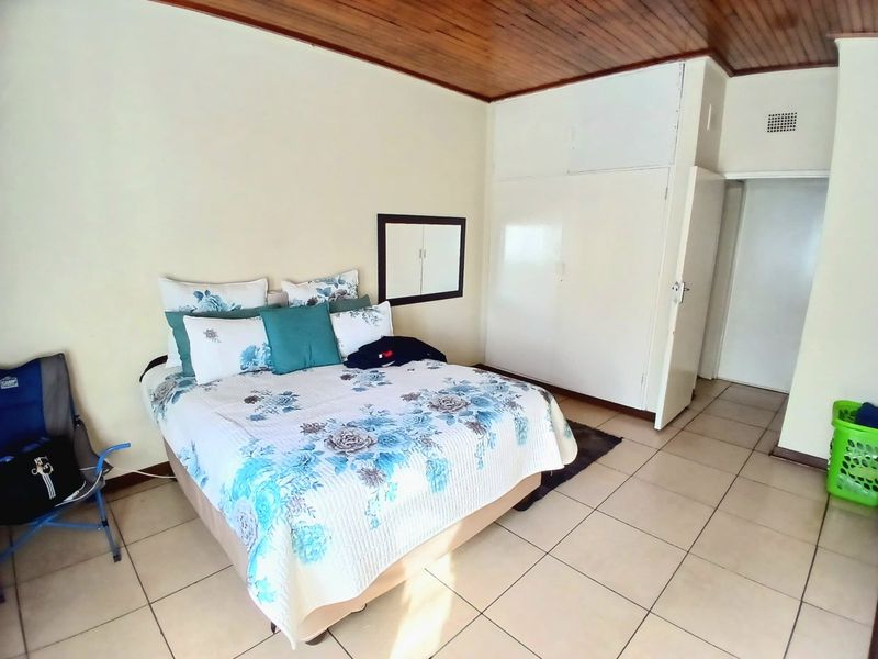 A bedroom featuring tiled flooring, a wooden ceiling, and built-in cupboards, providing a functional space with classic architectural elements.