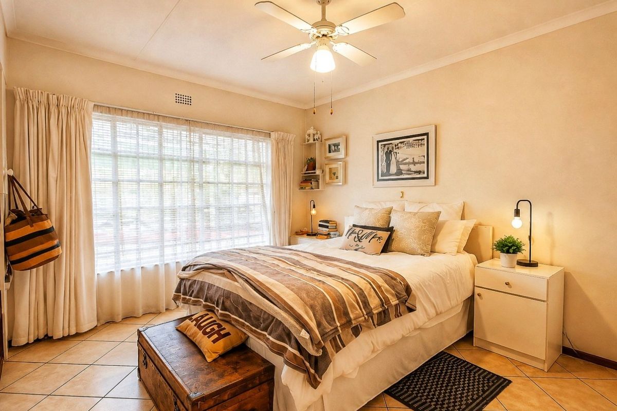 A well-maintained bedroom featuring tiled flooring, a central ceiling fan, and large windows with curtain tracks, offering a comfortable and functional living space.