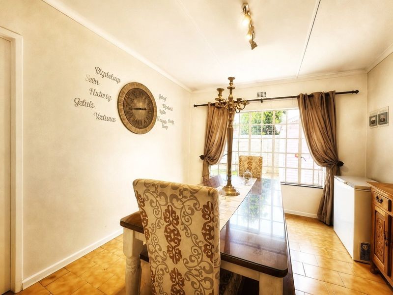 A dining room featuring tiled flooring, a window with security bars, and ceiling-mounted track lighting, providing a functional space for meals.