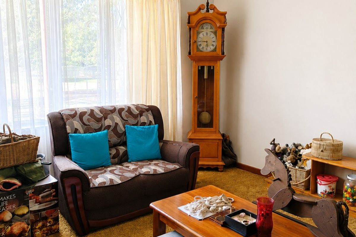 A living room featuring dated carpet flooring and a large window with curtain rod, offering a blank canvas for modernization.