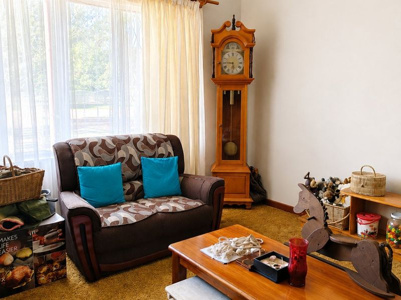 A living room featuring dated carpet flooring and a large window with curtain rod, offering a blank canvas for modernization.