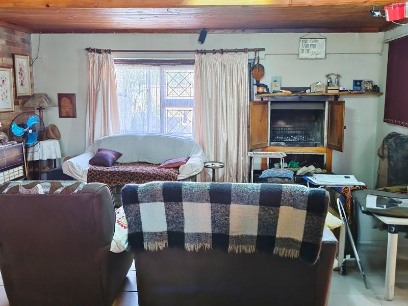 Living room featuring a timber ceiling, built-in fireplace, and tiled flooring, offering a cozy space with potential for modernization.