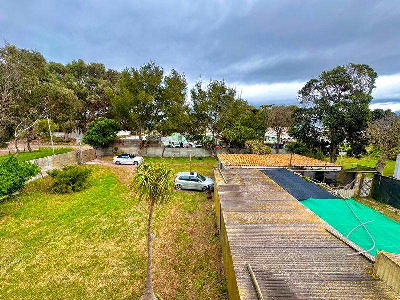 Aerial view of the property grounds featuring a large garden, driveway, and corrugated iron roofing on the outbuilding.