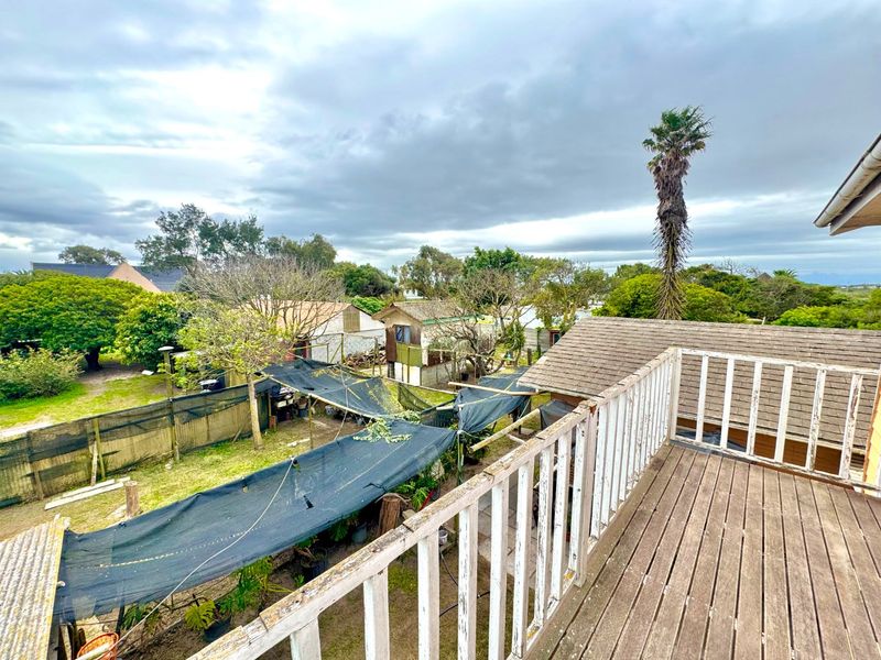 Elevated timber balcony overlooking the rear garden area, featuring a wooden balustrade and views of the surrounding property grounds.