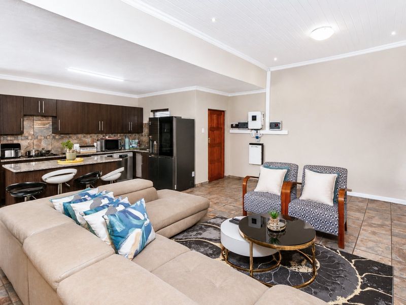 Spacious open-plan living area featuring a modern kitchen with granite countertops, breakfast bar, and tiled flooring throughout.