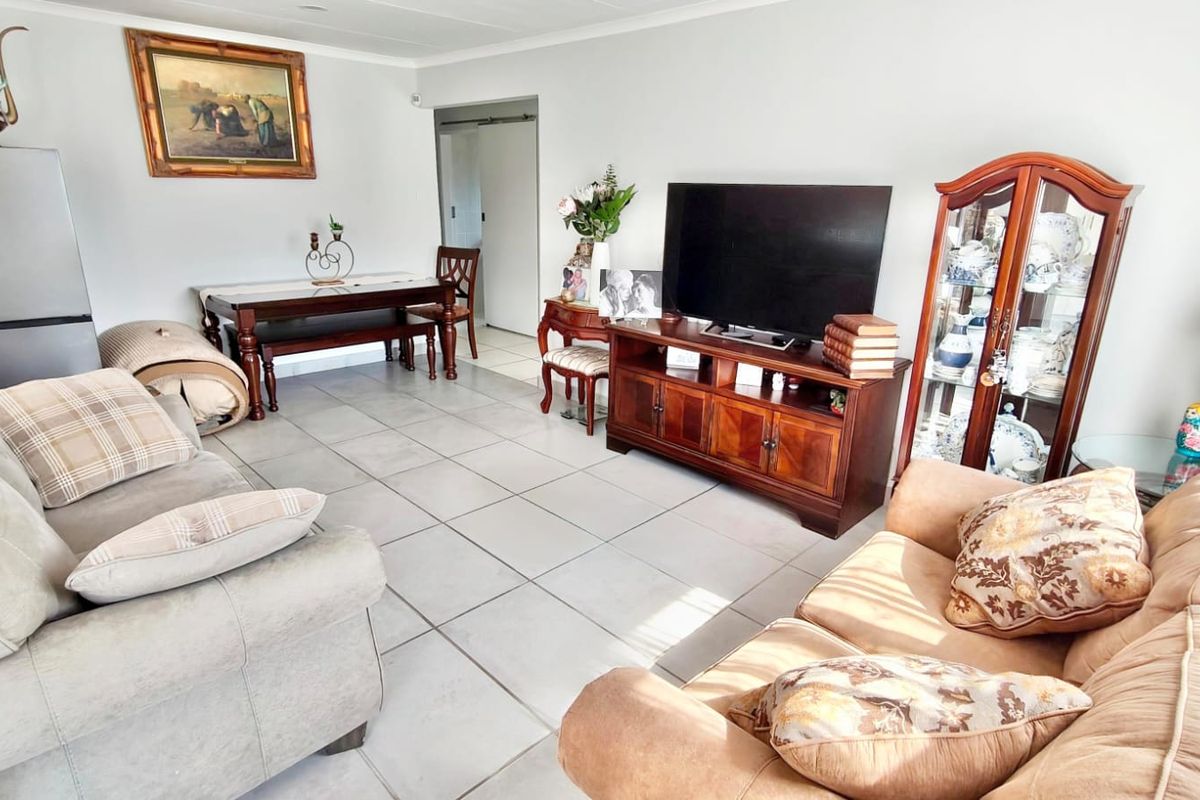 A spacious living area featuring neutral ceramic floor tiles and coved ceiling cornices, providing a functional and well-maintained base for interior design updates.