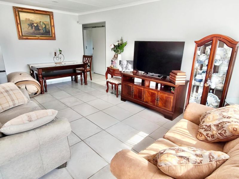 A spacious living area featuring neutral ceramic floor tiles and coved ceiling cornices, providing a functional and well-maintained base for interior design updates.