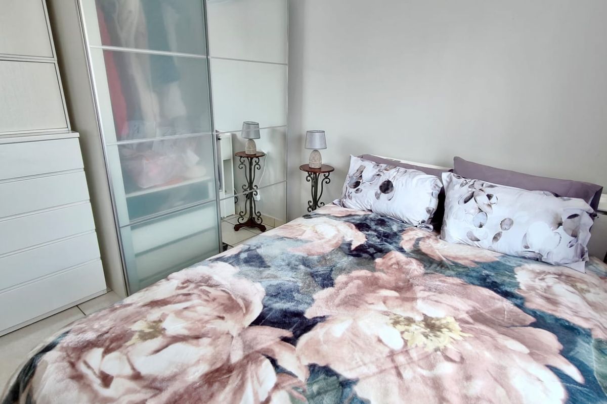 A bedroom featuring tiled flooring and a large built-in wardrobe with sliding doors.