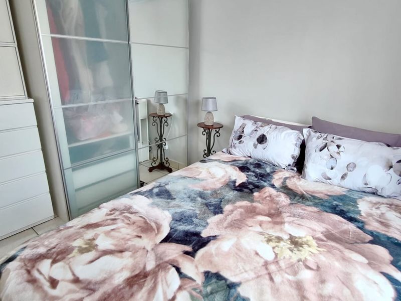 A bedroom featuring tiled flooring and a large built-in wardrobe with sliding doors.