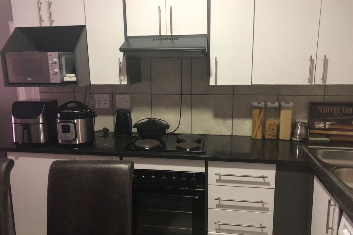A functional kitchen featuring white cabinetry, dark granite countertops, a built-in oven with electric hob, and a tiled backsplash.