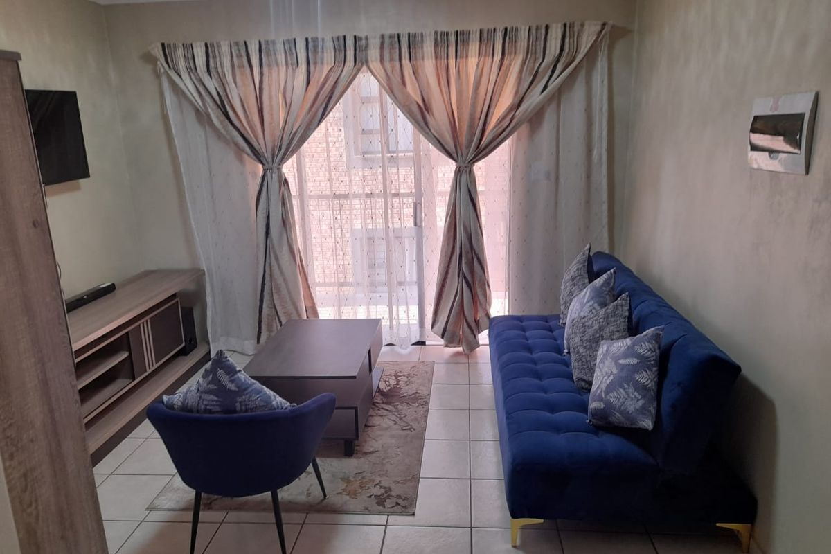 A comfortable living room featuring tiled flooring and a large sliding glass door that provides access to the balcony area.