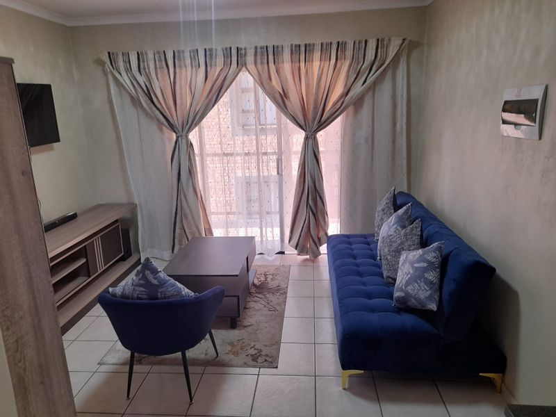 A comfortable living room featuring tiled flooring and a large sliding glass door that provides access to the balcony area.