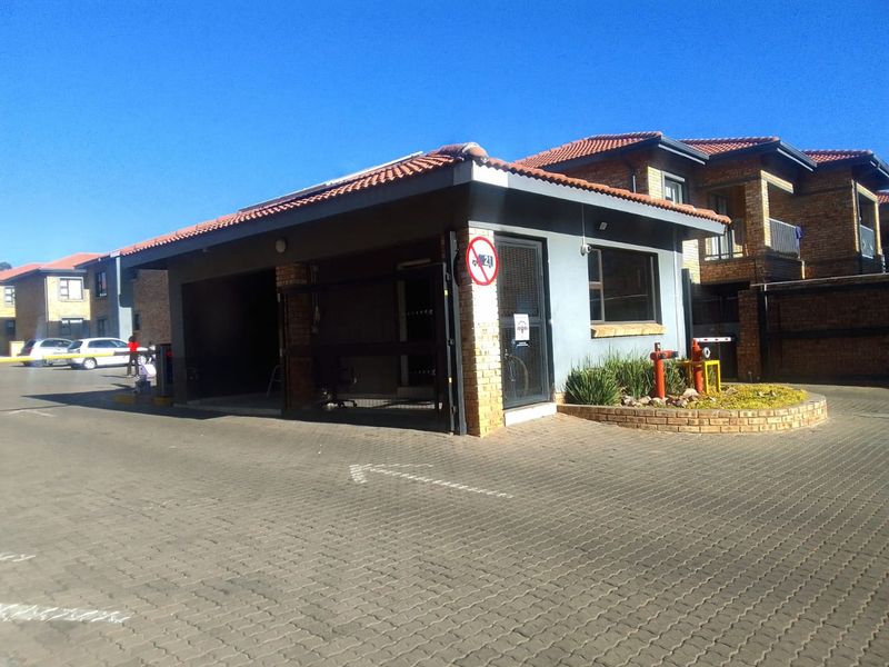The property features a secure gated entrance with a brick-built guardhouse, paved driveway access, and well-maintained exterior infrastructure.