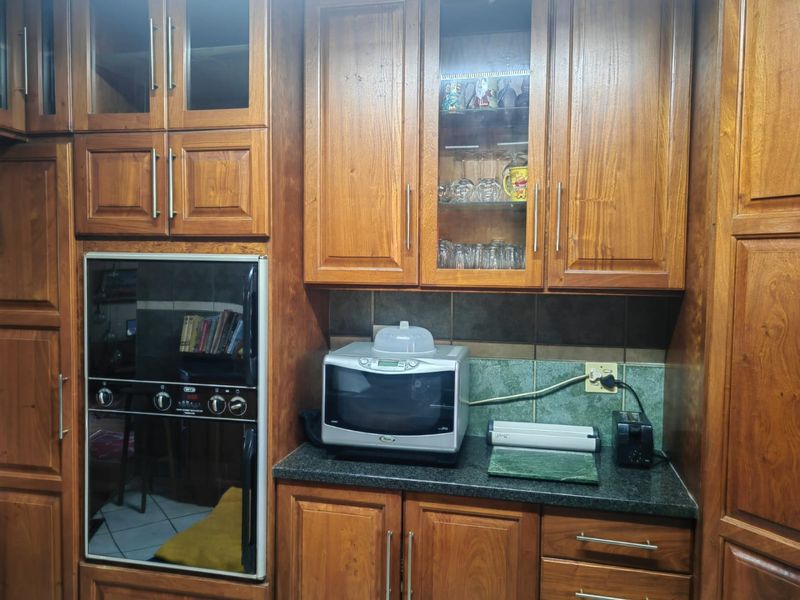 A kitchen area featuring traditional wooden cabinetry, a built-in oven, stone countertops, and a tiled backsplash.