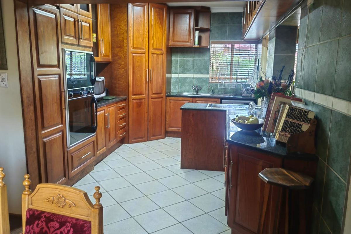 Traditional kitchen featuring extensive wooden cabinetry, granite countertops, built-in oven, and tiled finishes, offering a functional layout with ample storage space.