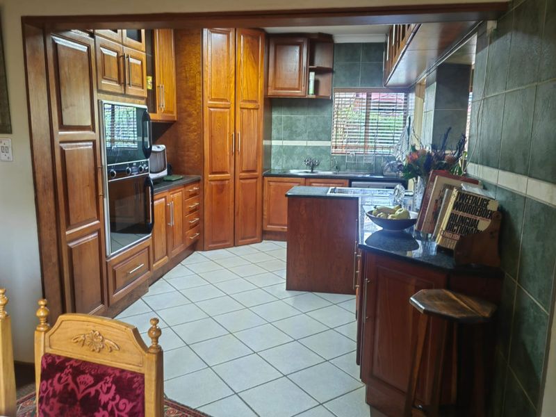 Traditional kitchen featuring extensive wooden cabinetry, granite countertops, built-in oven, and tiled finishes, offering a functional layout with ample storage space.