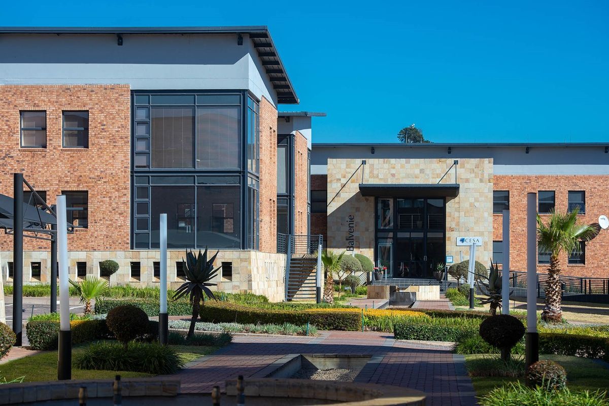 Professional exterior view of a modern commercial office building featuring brick and stone facade, large glass windows, and well-maintained landscaped grounds.