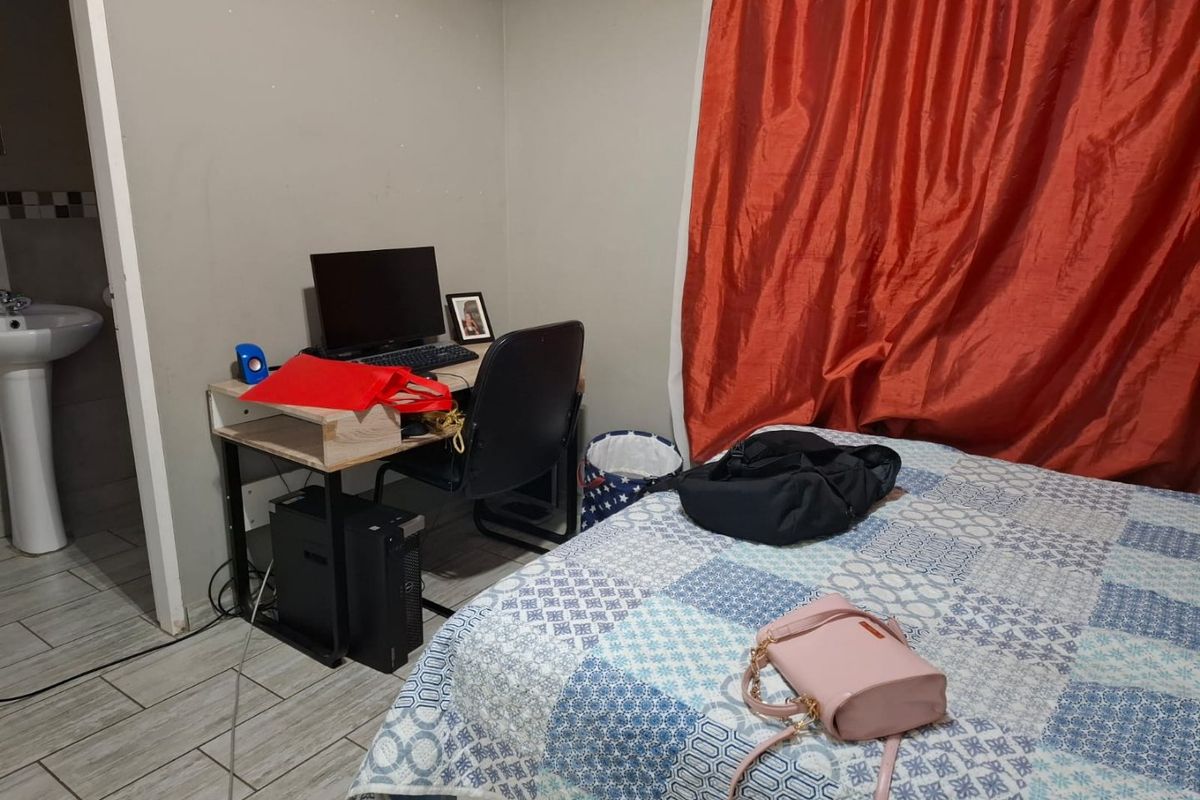 A bedroom featuring tiled flooring and an adjacent en-suite area with a pedestal basin.
