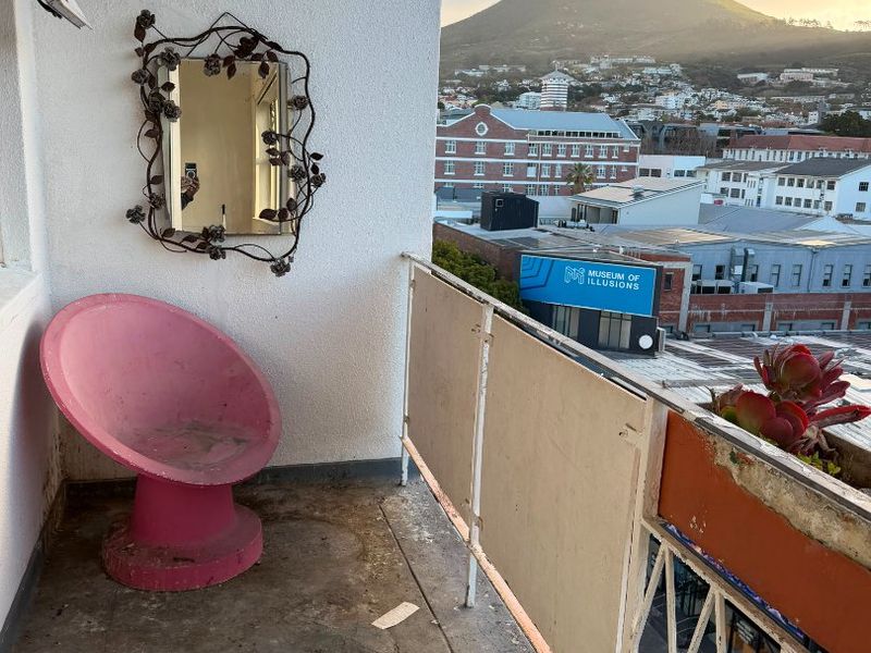 A balcony featuring a metal balustrade and views of the mountain, requiring maintenance to the flooring and railing finishes.