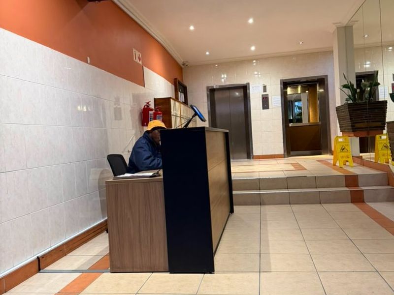 Apartment building entrance lobby featuring a reception desk, tiled flooring, and elevator access.
