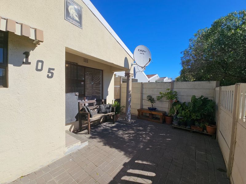Front entrance area featuring a paved patio, covered porch, and secure boundary walling, providing a functional and private approach to the home.