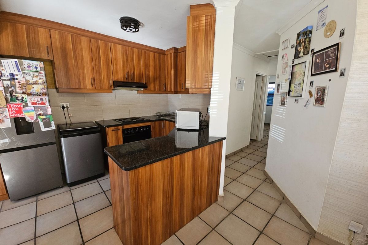 A functional kitchen featuring wood-finish cabinetry, granite countertops, a built-in oven with gas hob, and tiled flooring.