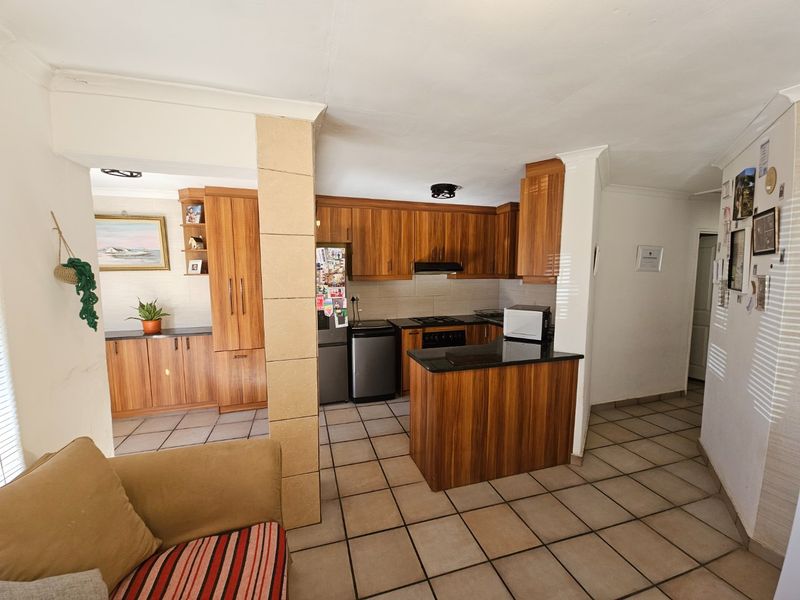Open-plan kitchen featuring wooden cabinetry, granite countertops, and tiled flooring, seamlessly integrated with the living area.