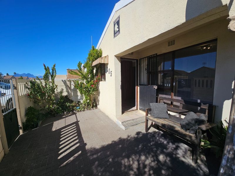 Front entrance area featuring paved driveway, security gate, and sliding glass door access to the home.