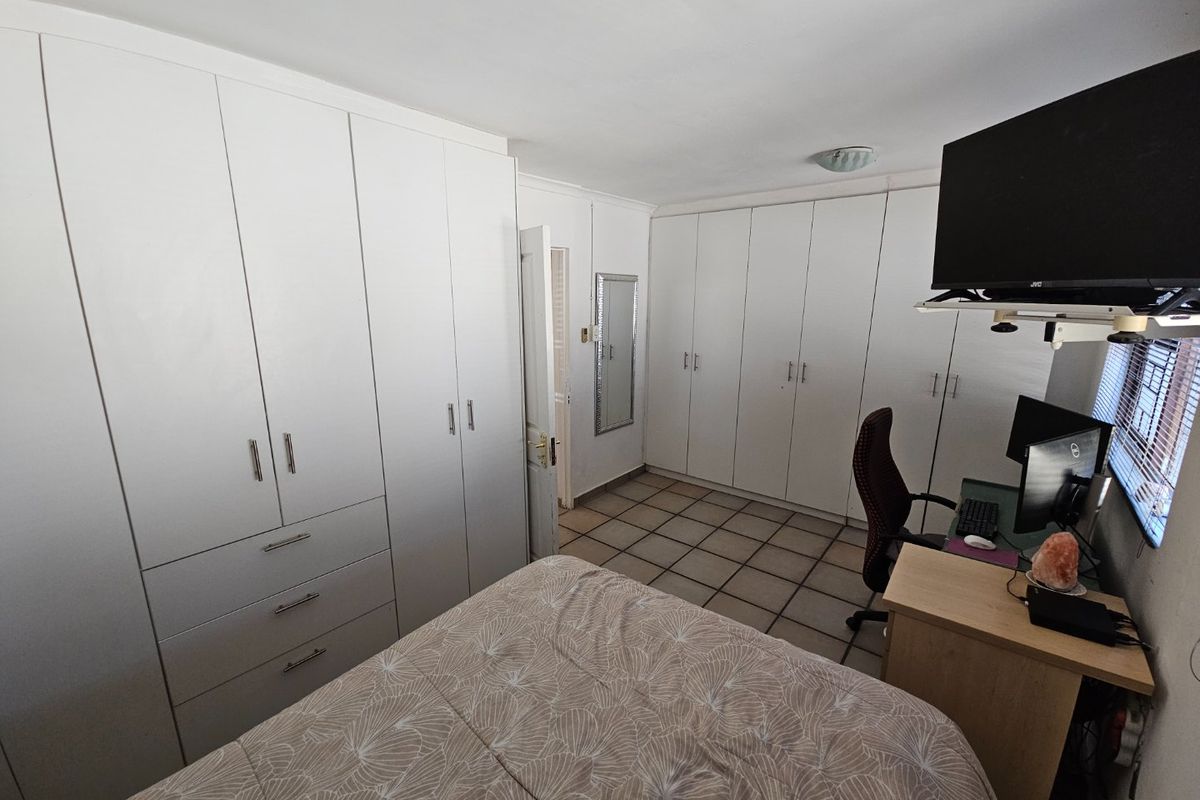A bedroom featuring extensive built-in white cabinetry for storage and tiled flooring throughout.