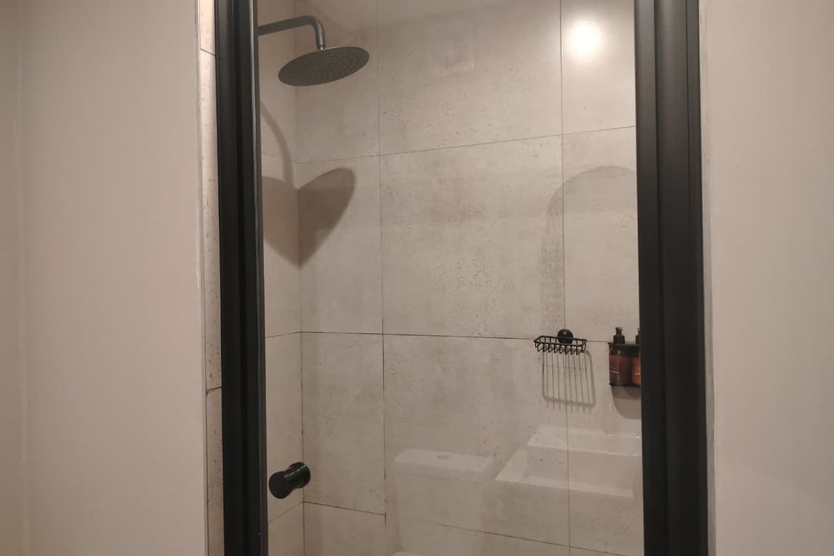 Modern bathroom featuring a walk-in shower with a rain shower head, black framed glass screen, and a built-in wall niche for storage.