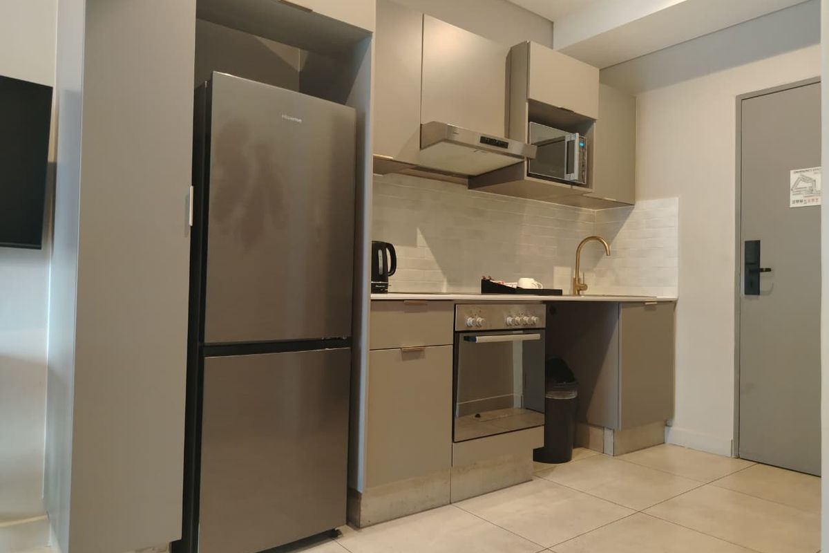 A modern, compact kitchen featuring sleek grey cabinetry, stainless steel appliances, a tiled backsplash, and contemporary fixtures.