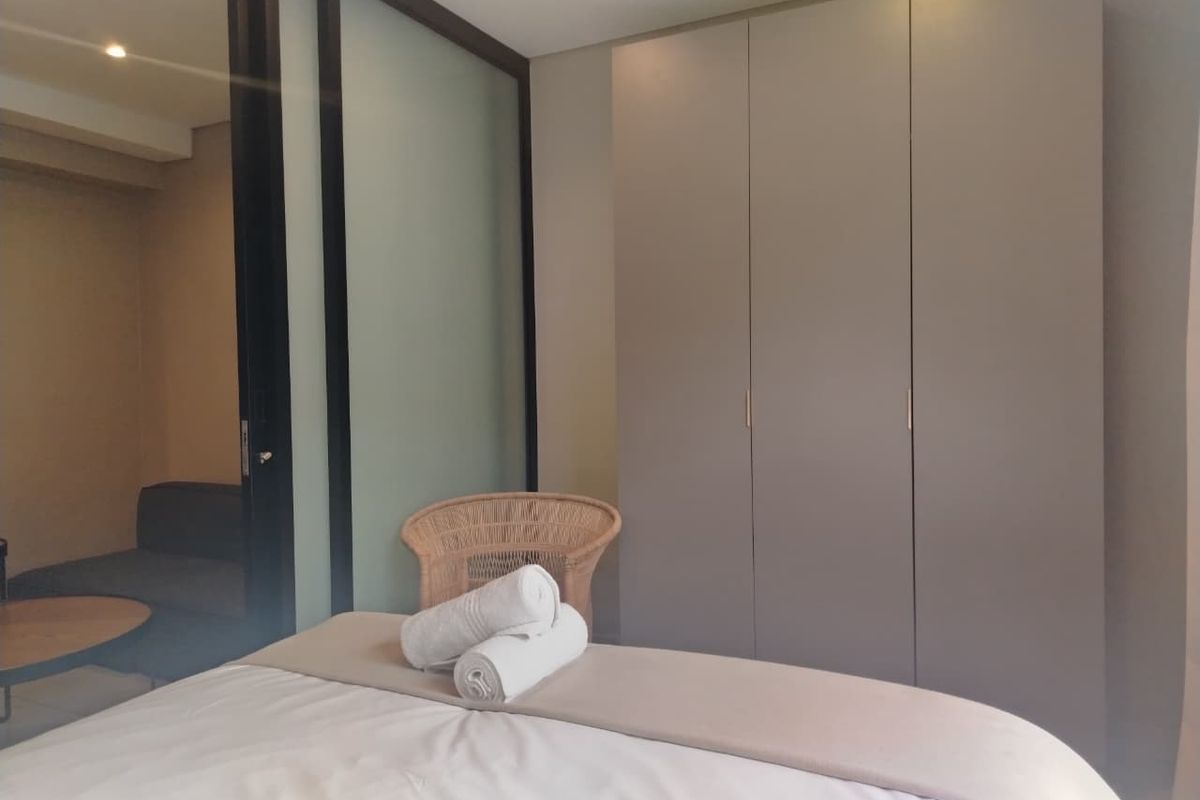 A modern bedroom featuring a large built-in wardrobe and a sleek sliding glass partition separating the sleeping area from the adjacent space.