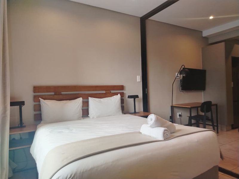 A well-maintained bedroom featuring neutral wall tones, recessed lighting, and integrated bedside shelving, creating a comfortable and functional living space.
