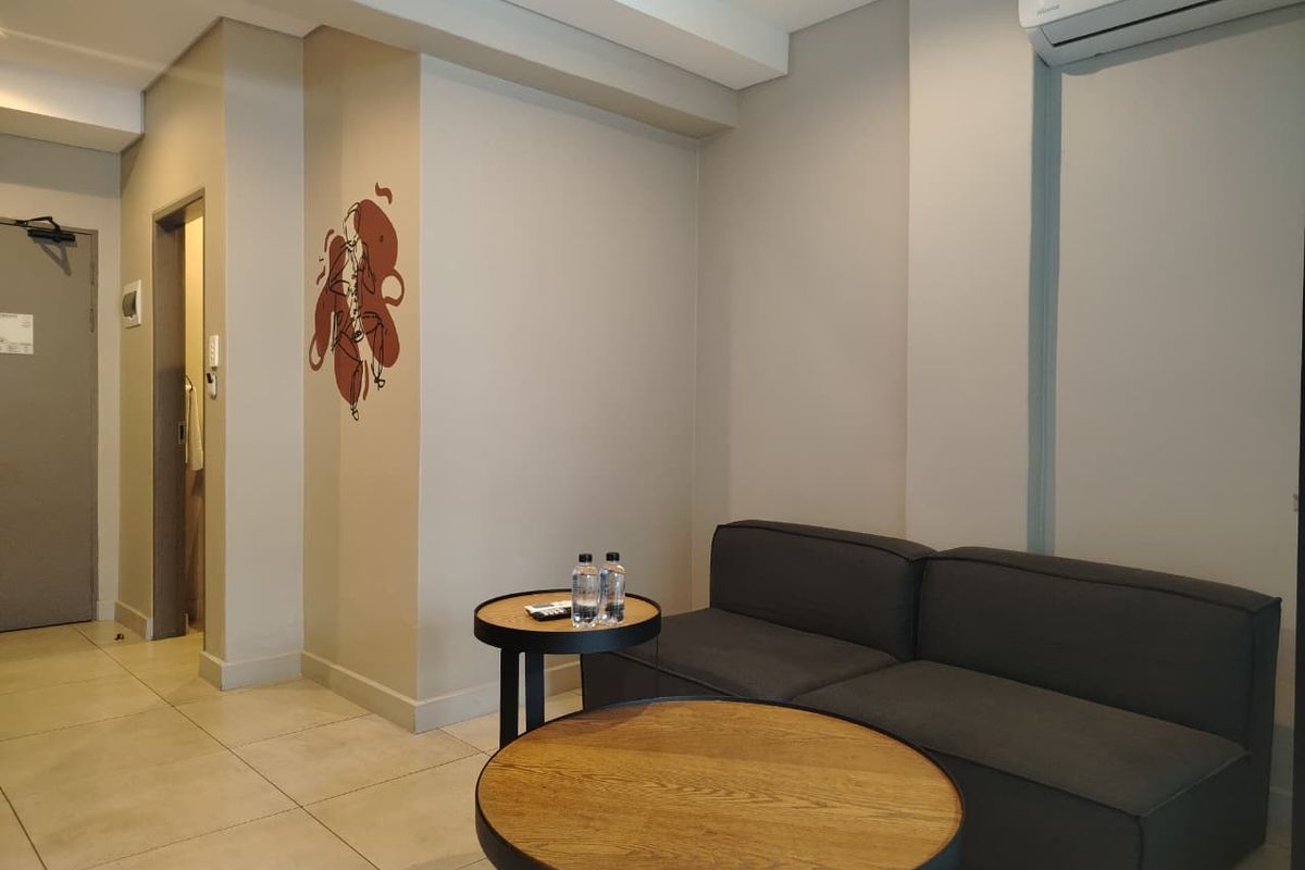 A modern living room featuring neutral wall tones, tiled flooring, and a wall-mounted split-system air conditioning unit.