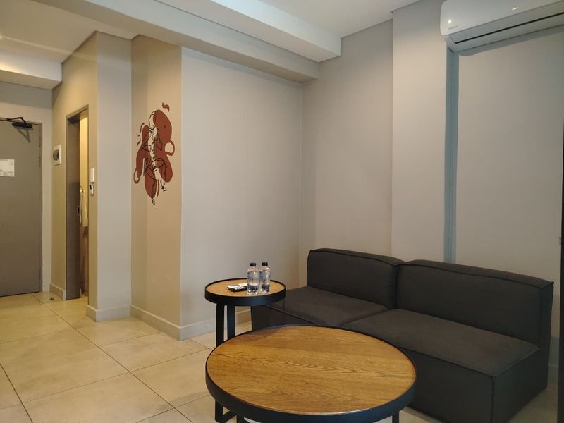 A modern living room featuring neutral wall tones, tiled flooring, and a wall-mounted split-system air conditioning unit.