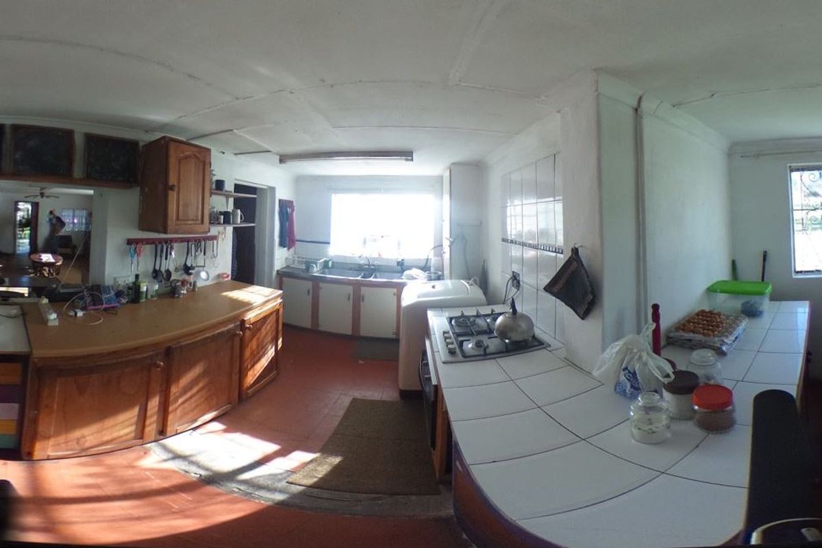 A spacious farm-style kitchen featuring tiled countertops, built-in wooden cabinetry, and a gas hob, offering a functional layout with ample natural light.