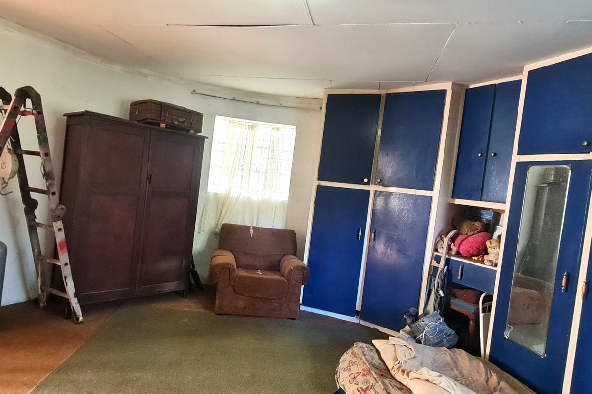 A bedroom featuring built-in blue cabinetry and a window, requiring cosmetic updates and ceiling repairs to improve the overall condition.