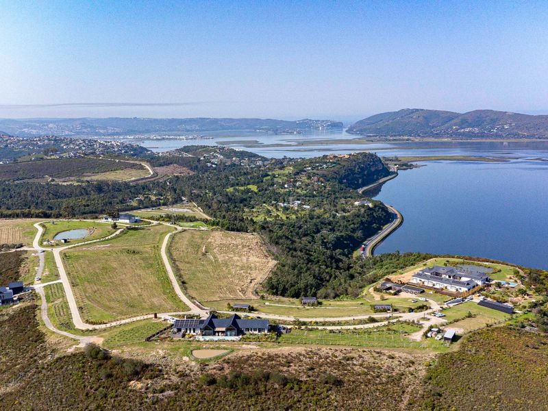Aerial view of a residential estate development featuring multiple dwellings, paved access roads, and scenic coastal landscape views.