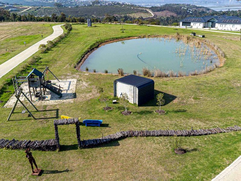 Aerial view of a residential estate featuring a landscaped pond, paved walking paths, and open green space.