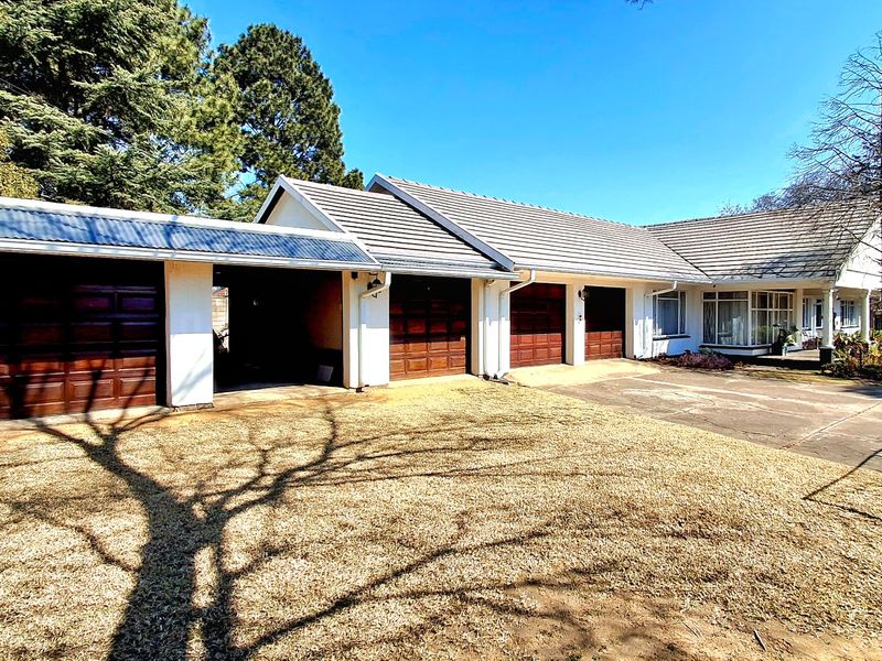 Front exterior view of the property featuring multiple garage doors, a covered carport, and a concrete driveway leading to the main entrance.