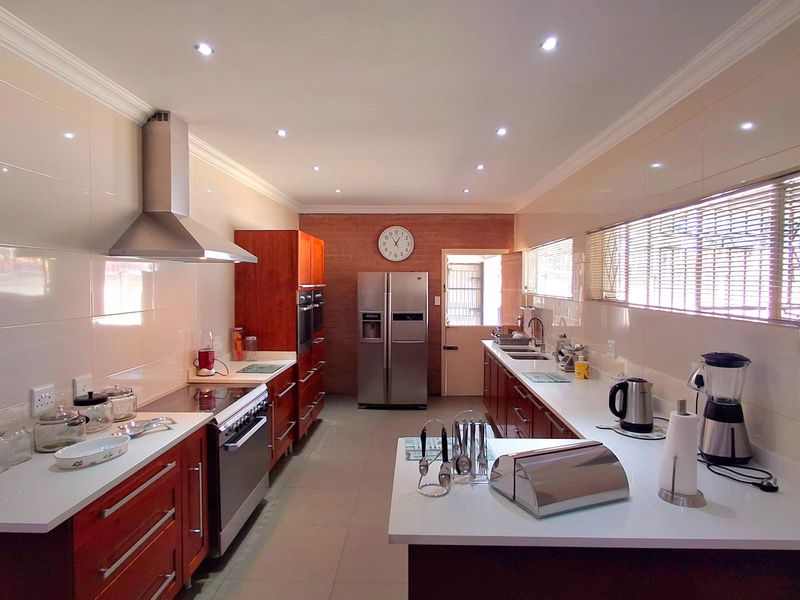 A spacious, well-lit kitchen featuring modern cabinetry, stone countertops, integrated stainless steel appliances, and a functional layout with ample workspace.