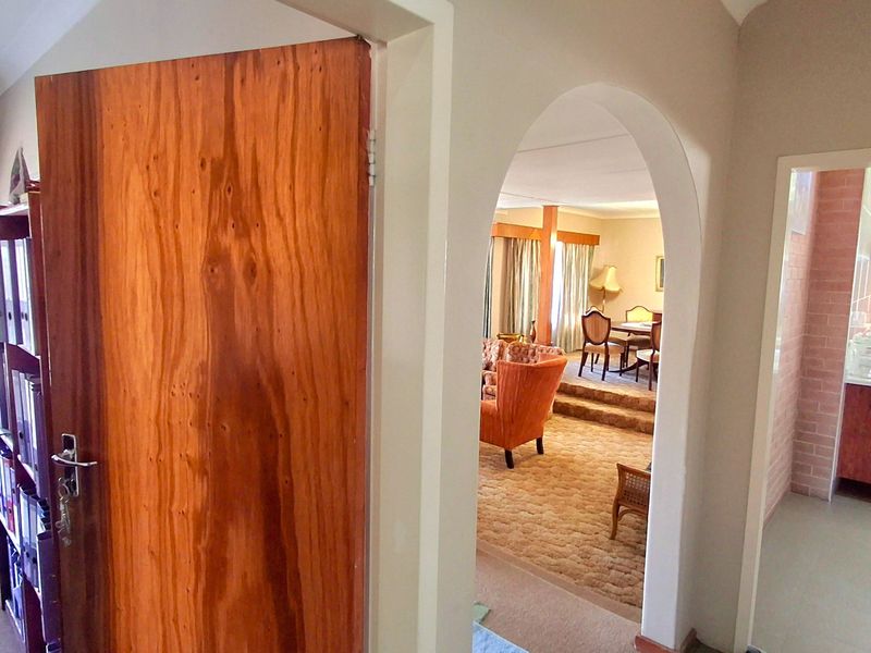 View through an arched doorway into an open-plan living and dining area with a sunken floor and adjacent kitchen space.