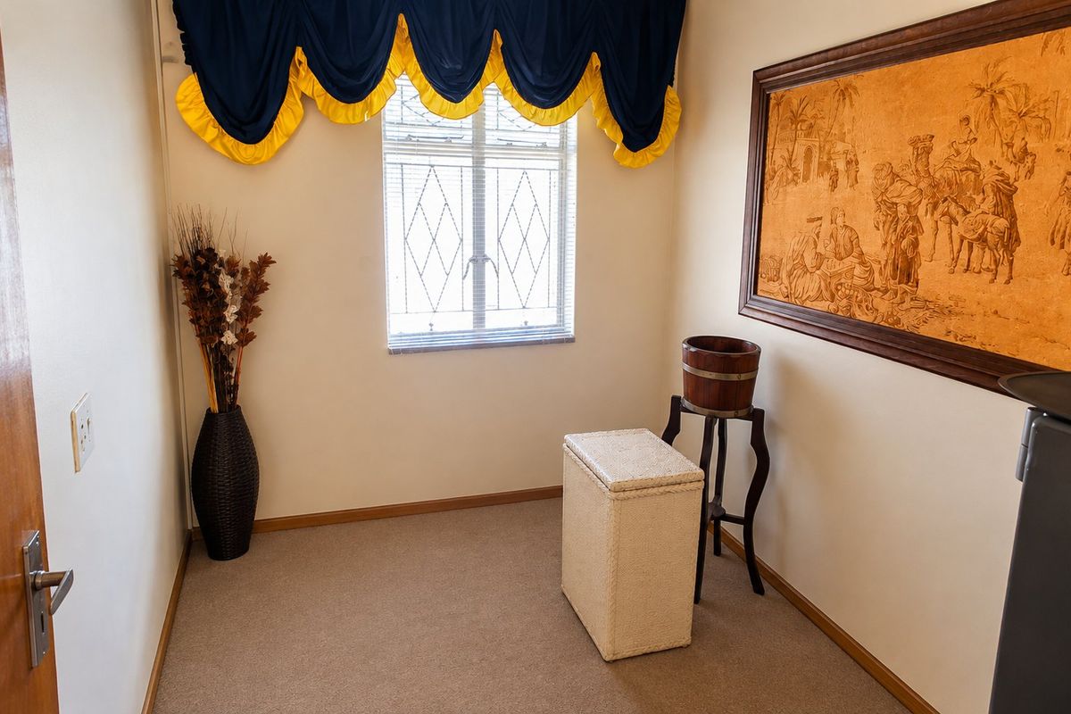 A carpeted bedroom featuring a window with security bars and neutral wall finishes, offering a clean and functional space.