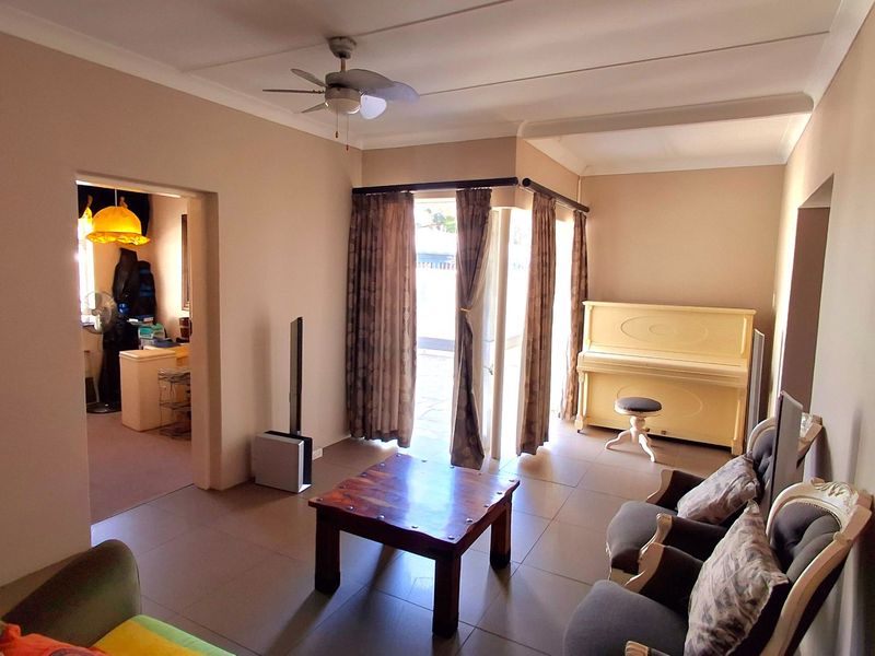 A living room featuring tiled flooring, a ceiling fan, and a sliding glass door providing access to the outdoor area.